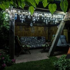 Zewnętrzne lampki LED sople oświetlające drewniany taras w ogrodzie